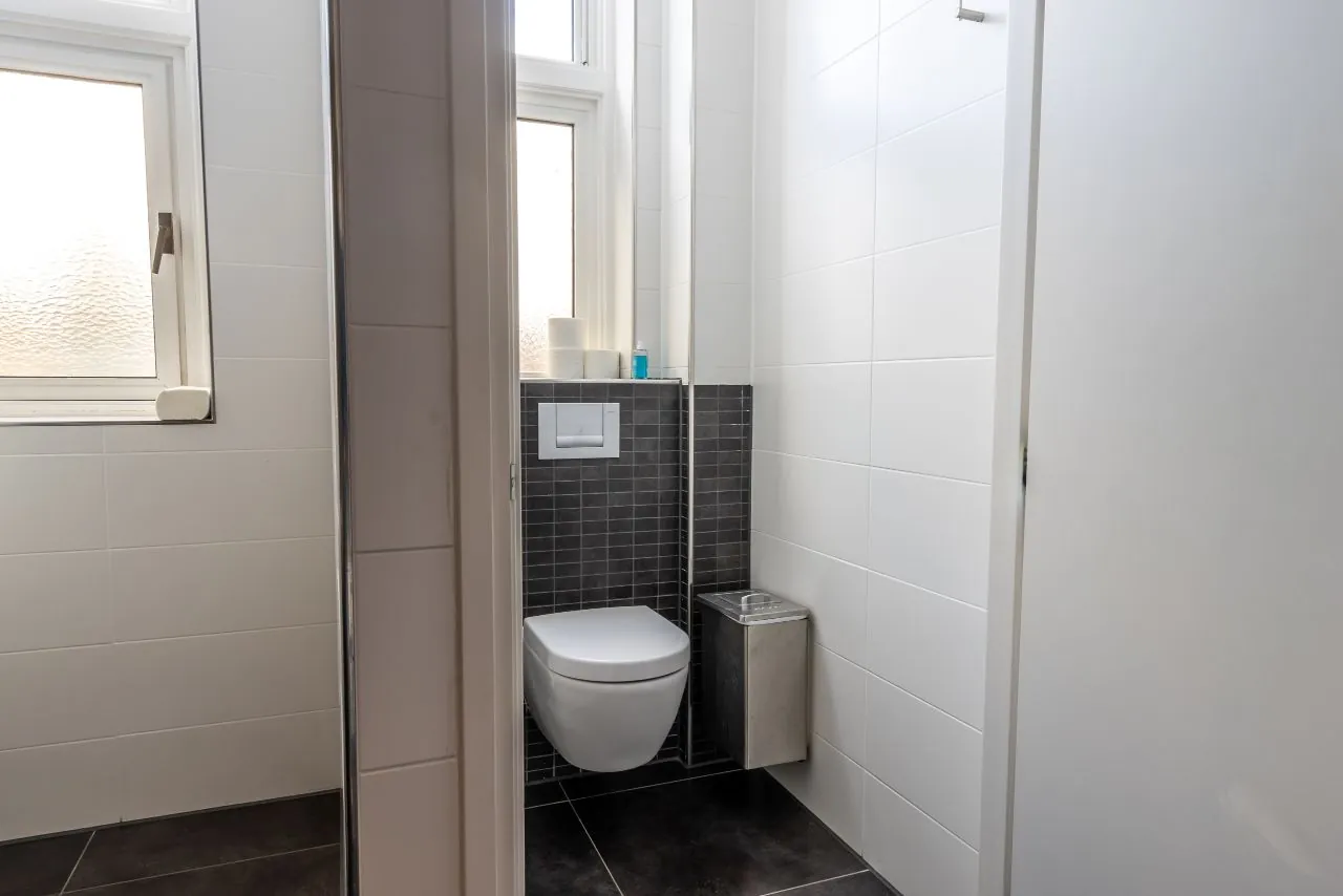 Modern toilet met hangend closet, zwarte tegelvloer en witte wandtegels aan de Lage Naarderweg.